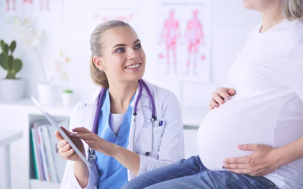 Il medico sorridente mostra le immagini sulla compressa a una giovane donna incinta in ospedale. — Foto Stock