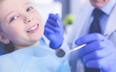 Küçük kız dişçi ofisinde oturuyor.