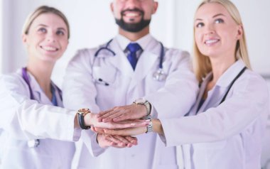 Doktorlar ve hemşireler tıbbi bir ekipte el ele tutuşuyorlar.