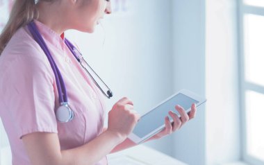 Doktor kadın tablet bilgisayardaki tıbbi verileri kontrol ediyor.