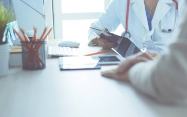 Bir doktor konuşuyor ve bir hastayı muayene ediyor.