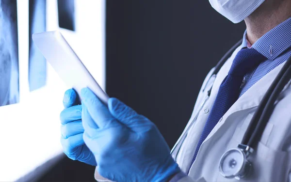 Orvos a kórházban ül íróasztal nézi röntgen tabletta fehér háttér röntgen — Stock Fotó