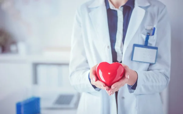 Un médecin avec stéthoscope examinant le cœur rouge, isolé sur fond blanc — Photo