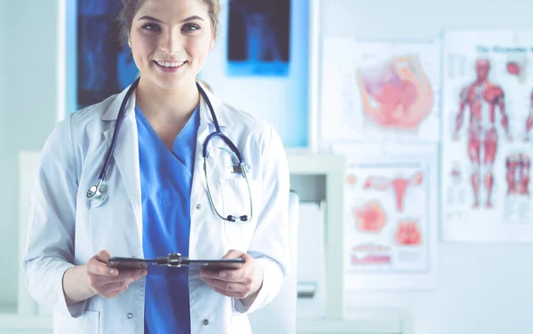 Glimlachende vrouwelijke arts met een map in uniform staand — Stockfoto