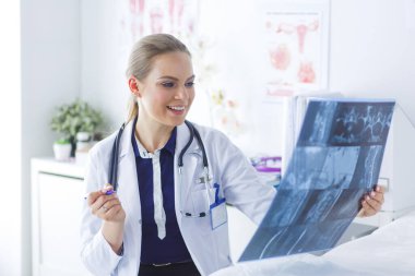 Genç ve çekici bayan doktor röntgen görüntülerine bakıyor.