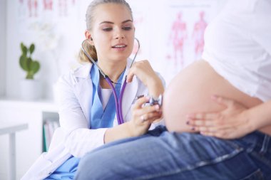 Steteskoplu genç bayan doktor hastanede hamile bir kadınla konuşuyor..