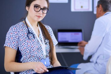 Bir doktor ekibi, kadın ve erkek, ofiste bekliyorlar.