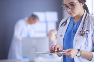 Hastane lobisinde tablet bilgisayar kullanan kadın doktor.