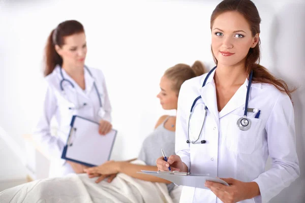 Médico sonriente con una carpeta en uniforme de pie en el hospital — Foto de Stock