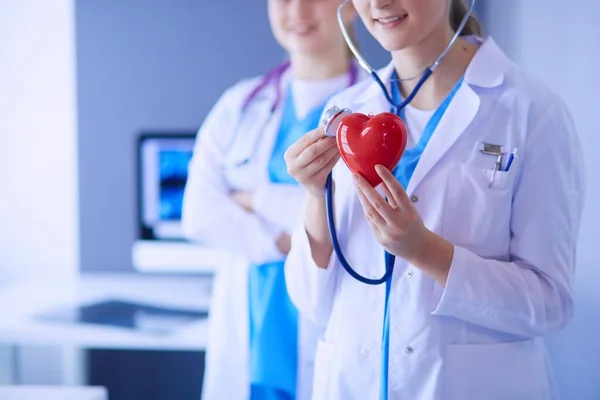 Abgeschnittene Aufnahme zweier junger Ärztinnen mit Stethoskop am Herzen. — Stockfoto