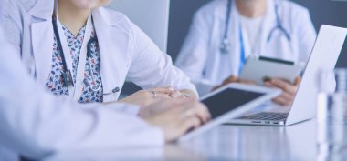 Ciddi bir tıbbi ekip parlak bir ofiste dizüstü bilgisayar kullanıyor.