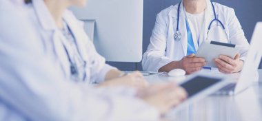 Ciddi bir tıbbi ekip parlak bir ofiste dizüstü bilgisayar kullanıyor.