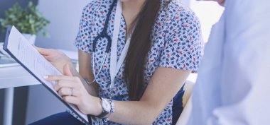 Parlak bir ofiste konuşan iki doktor.