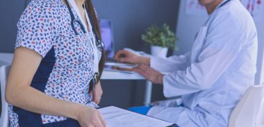 Parlak bir ofiste konuşan iki doktor.