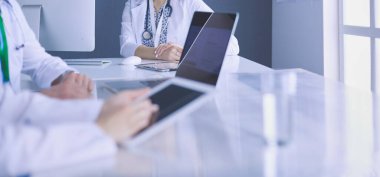 Ciddi bir tıbbi ekip parlak bir ofiste dizüstü bilgisayar kullanıyor.