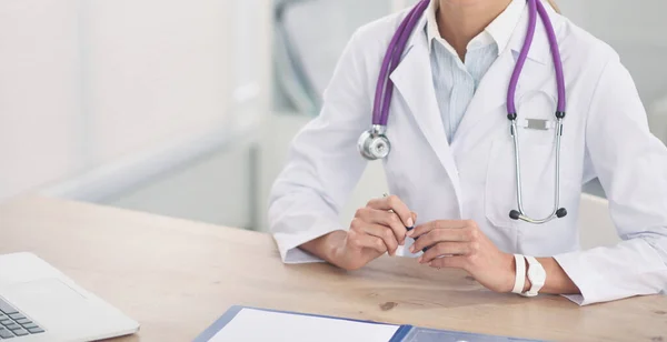 Hermosa joven sonriente doctora sentada en el escritorio y escribiendo. —  Fotos de Stock