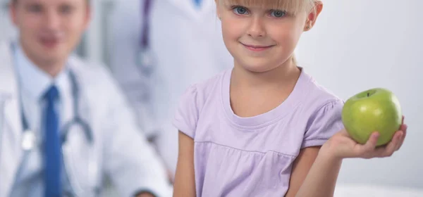 Ребенок и медицина концепция - женщина врач давая яблоко улыбающейся маленькой девочке — стоковое фото