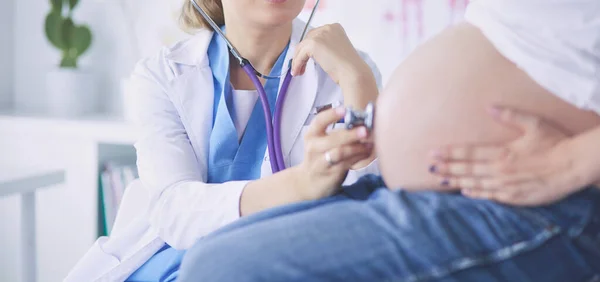 Doctora joven con estetoscopio hablando con una mujer embarazada en el hospital . — Foto de Stock