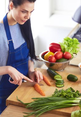 Mutfakta sebze doğrayan genç bir kadın.