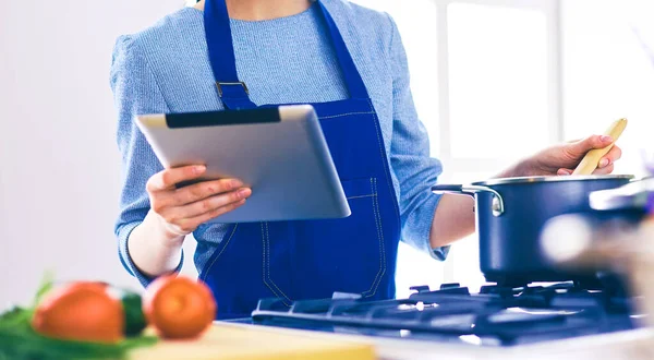 Mutfakta yemek yapmak için tablet bilgisayar kullanan genç bir kadın. — Stok fotoğraf