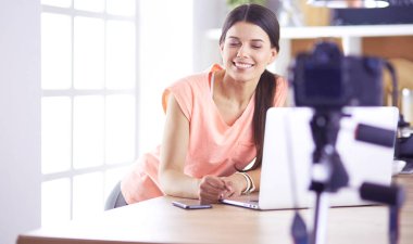 Mutfakta dizüstü bilgisayara benzeyen tariflerle gülümseyen genç bir kadın. Gıda blogcusu kavramı