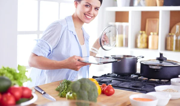 Jonge vrouw bij het fornuis in de keuken — Stockfoto