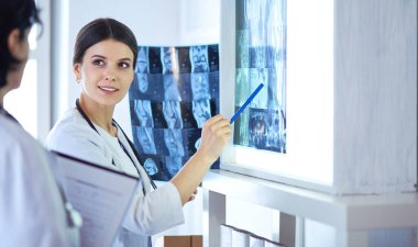 İki gülümseyen doktor hastane muayene odasında röntgenleri gösteriyor.