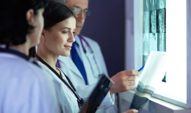 Bir grup doktor bir klinikte röntgenleri inceliyor, teşhis koymayı düşünüyorlar.