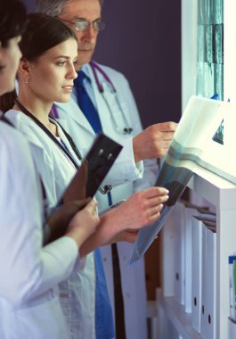 Bir grup doktor bir klinikte röntgenleri inceliyor, teşhis koymayı düşünüyorlar.