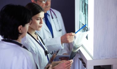 Bir grup doktor bir klinikte röntgenleri inceliyor, teşhis koymayı düşünüyorlar.
