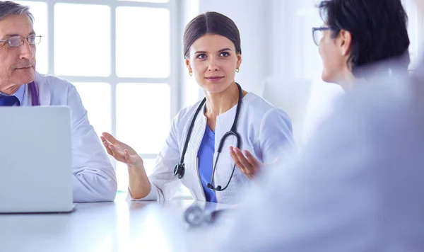 Serieuze medische team met behulp van een laptop in een heldere consulting room — Stockfoto