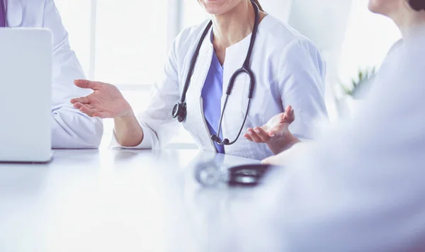 Equipo médico serio discutiendo casos de pacientes en un consultorio luminoso —  Fotos de Stock