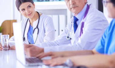 Parlak bir hastane odasında meslektaşlarıyla çalışan gülümseyen bir doktor.