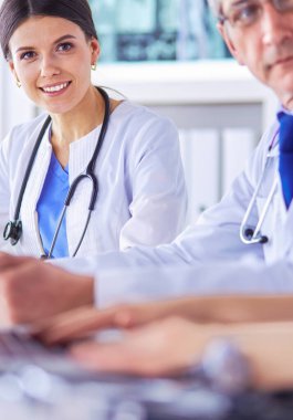 Parlak bir hastane odasında meslektaşlarıyla çalışan gülümseyen bir doktor.