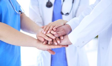 Bir grup doktor ellerini birleştiriyor. Yakın plan.