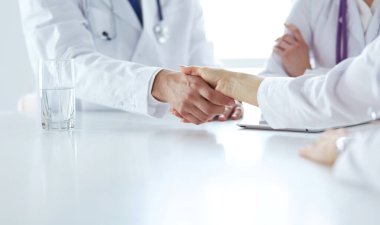 Doktor ofiste erkek bir hastayla el sıkışıyor.