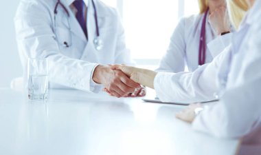 Doktor ofiste erkek bir hastayla el sıkışıyor.
