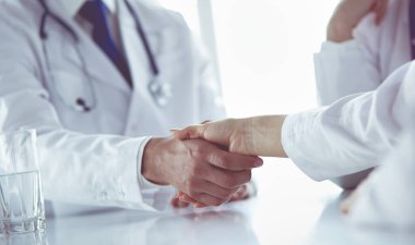 Doktor ofiste erkek bir hastayla el sıkışıyor.