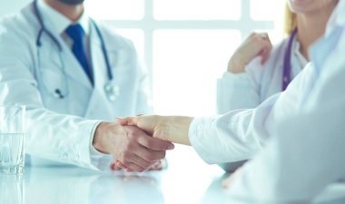 Doktor ofiste erkek bir hastayla el sıkışıyor.