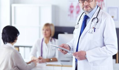 Boynunda steteskopla kameraya bakan bir doktor.