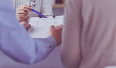 Doktor ve hasta tıbbi kayıtları olan bir dosyayı inceliyor. Tekerlekli sandalyede oturuyor.