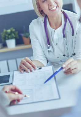 Doktor ve hasta tıbbi kayıtları olan bir dosyayı inceliyor. Tekerlekli sandalyede oturuyor.