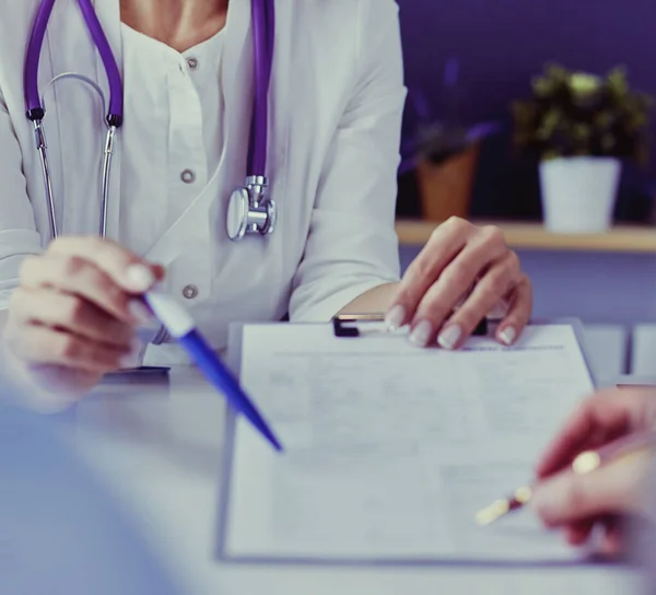 Doctor and patient examining a file with medical records, she is sitting on a wheelchair — Stock Photo, Image