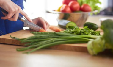 Mutfakta sebze doğrayan genç bir kadın.