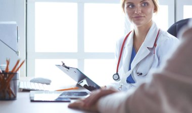 Bir doktor konuşuyor ve bir hastayı muayene ediyor.