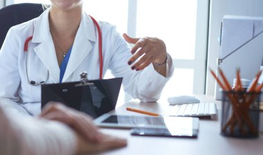 Bir doktor konuşuyor ve bir hastayı muayene ediyor.