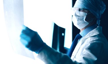 Genç doktor, izole edilmiş beyaz arka planda röntgen görüntüsü arıyor.