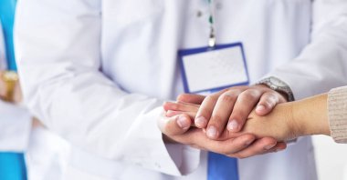 Doktorlar ve hemşireler tıbbi bir ekipte el ele tutuşuyorlar.