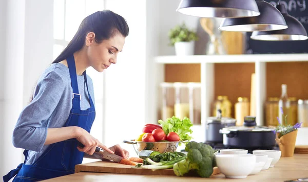 Jovem mulher cortando legumes na cozinha em casa — Fotografia de Stock