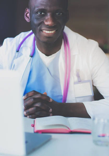 Молодий африканський лікар працює на ноутбуці за столом. Докторе. робоче місце — стокове фото